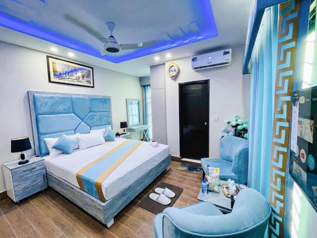 a bedroom with a bed and two blue chairs at Hotel Johar View in Lahore