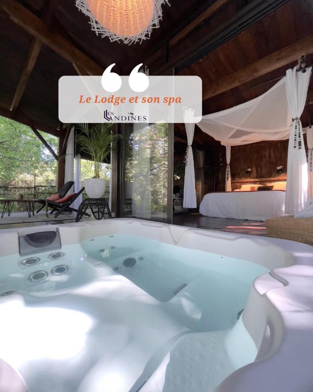 a jacuzzi tub in a room with a bed at Cabanes et Spa Les Landines in Origne