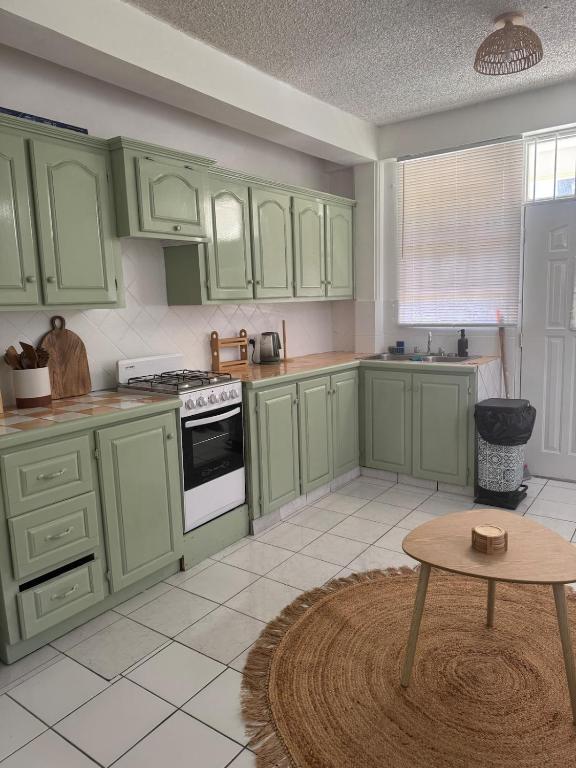 a kitchen with green cabinets and a table in it at Papaya Condo in Portsmouth