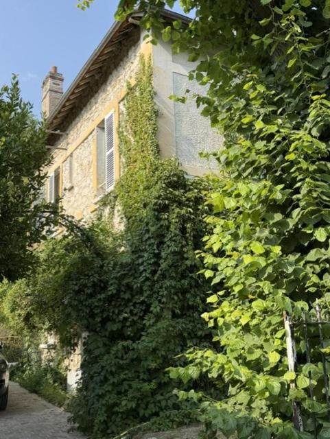 a building covered in ivy next to a house at Villa Mayeux in Giverny