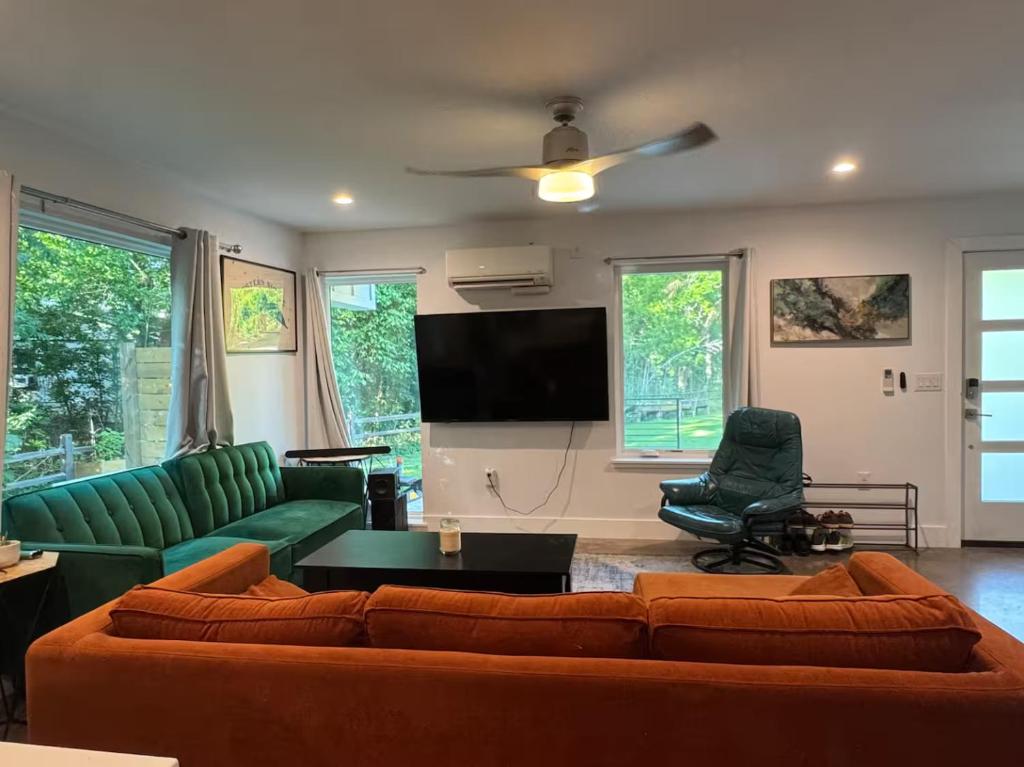 a living room with a couch and a flat screen tv at 1 full bed with En-Suite bath surrounded by greenery in Austin