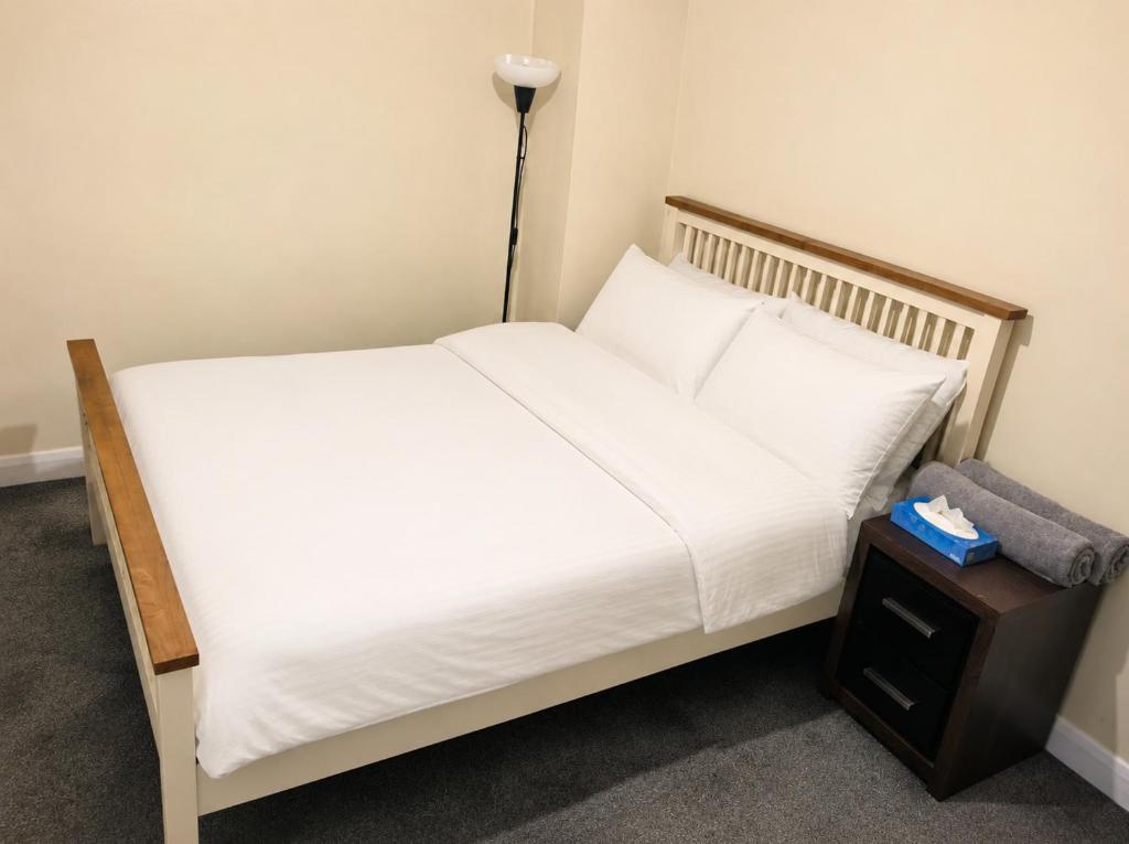 a bed with white sheets and a night stand at DD Private Double Room with Shared Bathroom in York