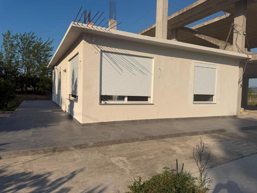a white house with a window with blinds on it at Villa Hasani in Hamallë