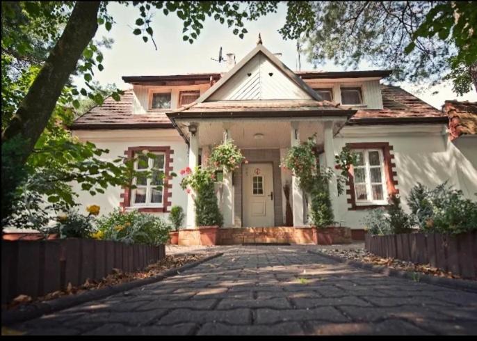 a large white house with a stone driveway at Dwór Złoty Bażant in Olsztyn