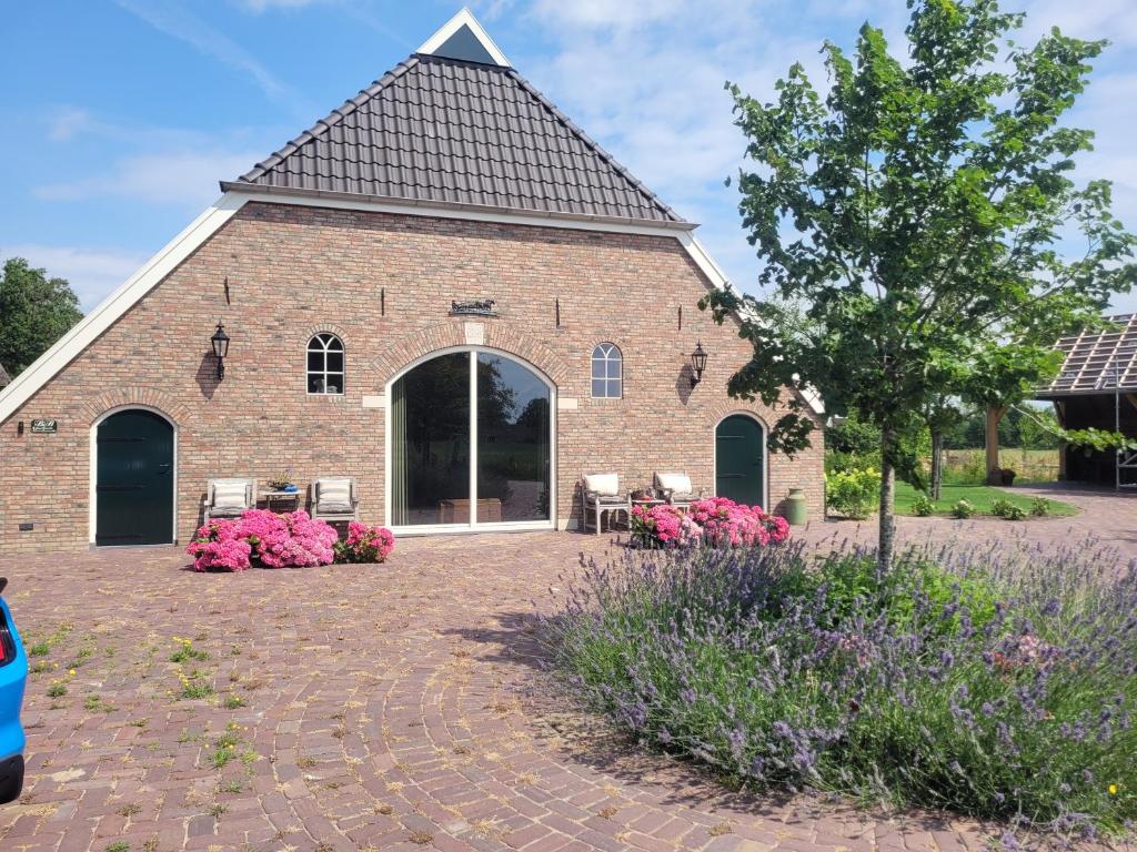 a large brick building with a patio and flowers at De Oranjehoeve in Holthone