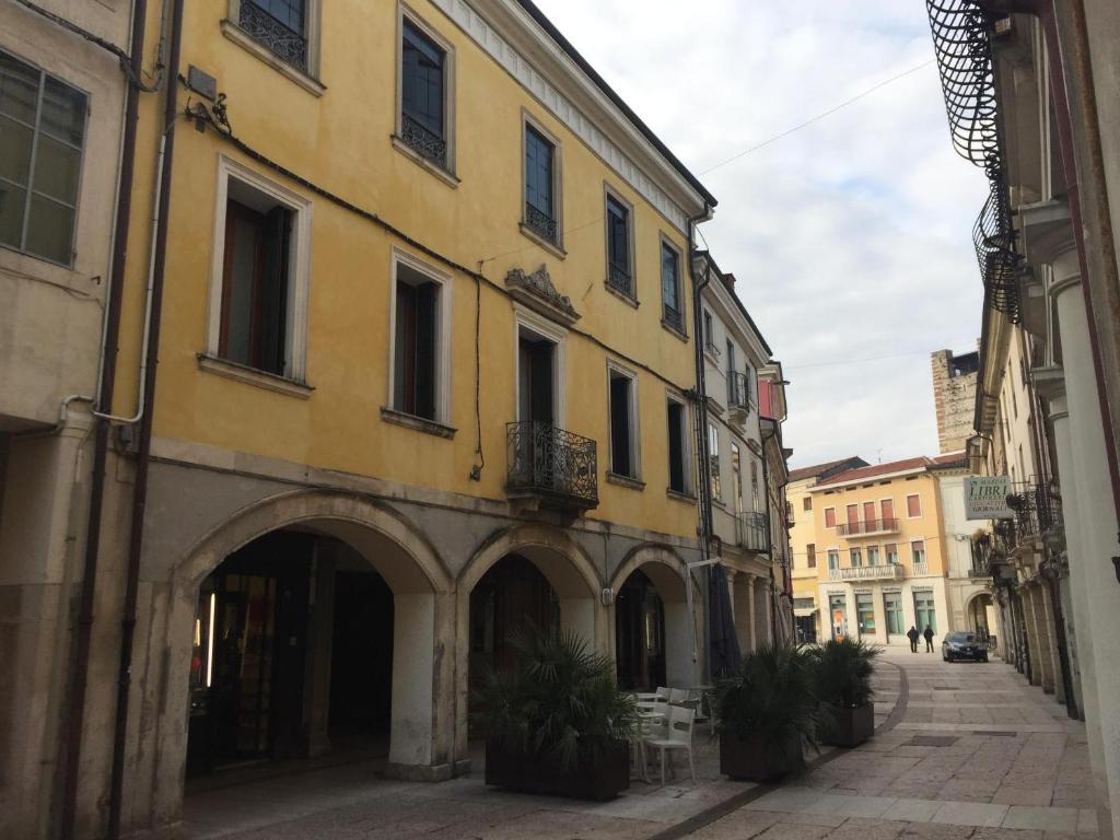 a yellow building with an arch in a street at B&B Via Garibaldi in Lonigo