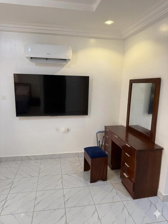 a room with a dresser and a mirror and a television at Asibbey Lodge in Ashalebotwe