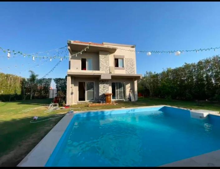 a house with a swimming pool in front of a house at فيلا رامي رزق Luxury villa with private pool& complete privacy in 6th Of October