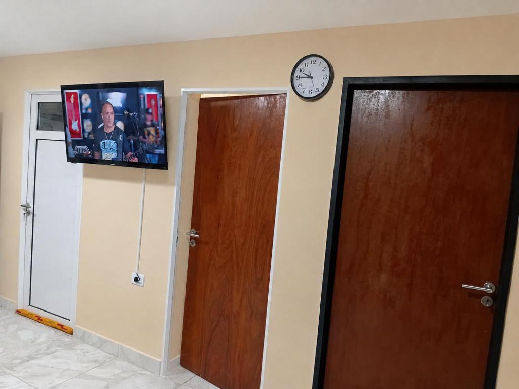 a clock on a wall above two doors and a tv at Apartamento Patagonia in Puerto San Julián
