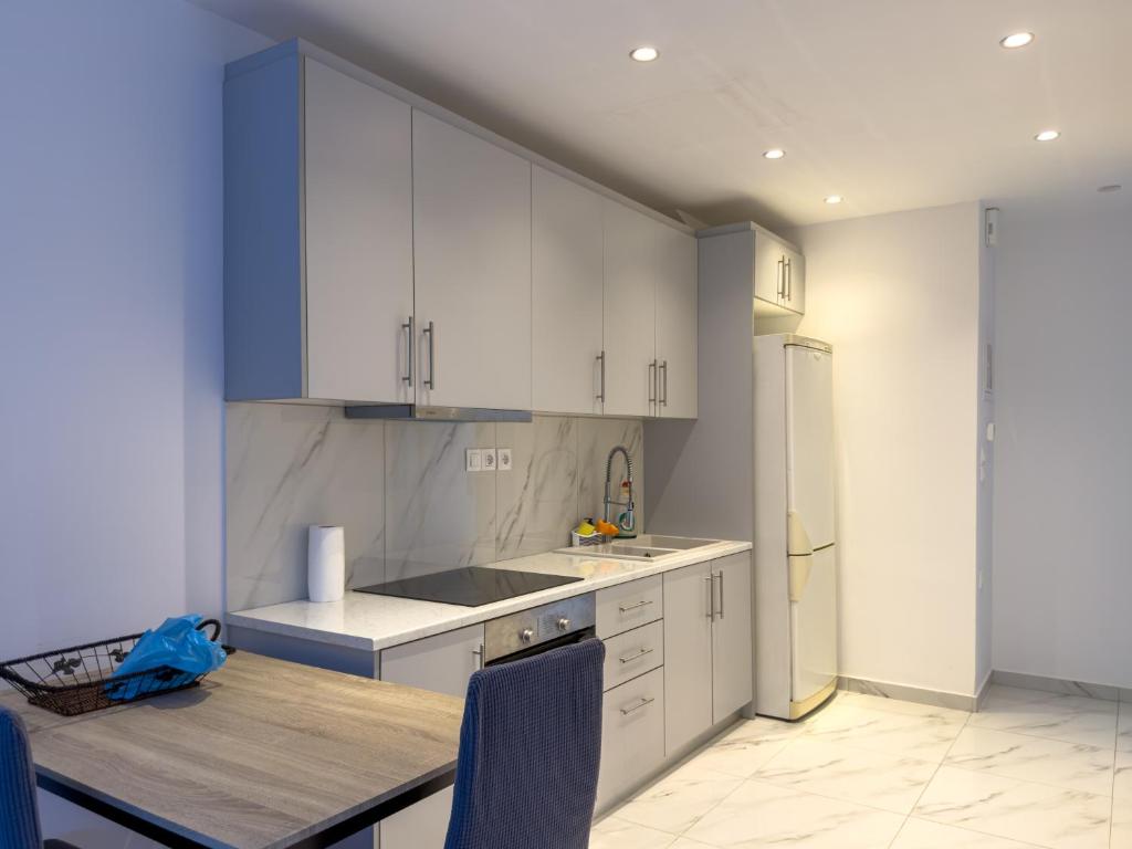 a kitchen with white cabinets and a table with blue chairs at Modern Comfort Apartment - Arkitsa Rentals in Arkitsa