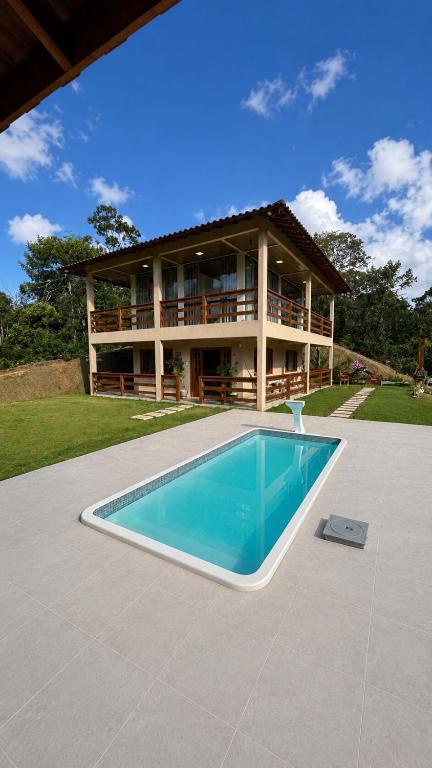 a house with a swimming pool in front of a house at Recanto HipoMar in Marechal Floriano