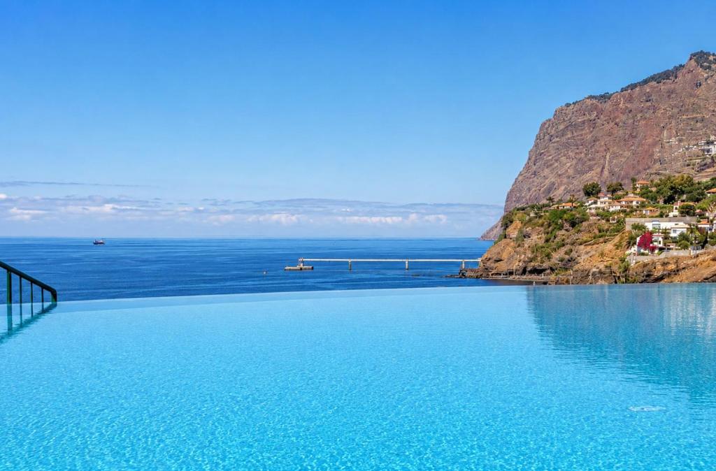 a large pool of blue water next to a mountain at Atlantic Ocean View Apartment in Funchal