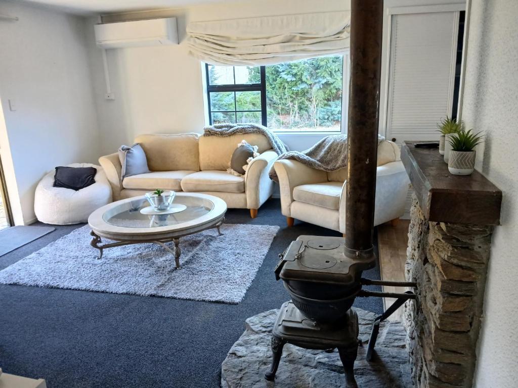 a living room with a wood stove and a couch at Cardrona mountain cottage in Cardrona