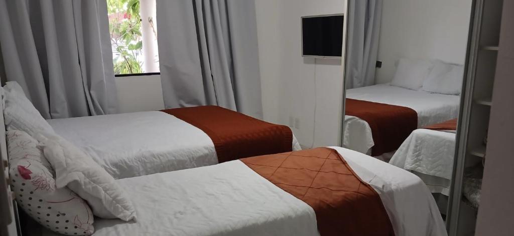 a hotel room with two beds and a mirror at Condomínio Sol Marina in Camaçari