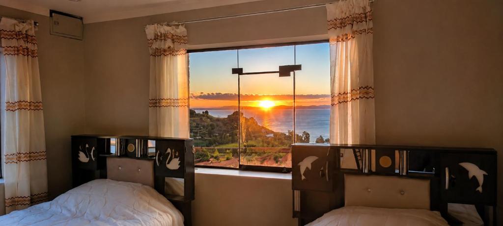 a bedroom with two beds and a window with the sunset at Dawn House - Lago Titicaca in Ocosuyo