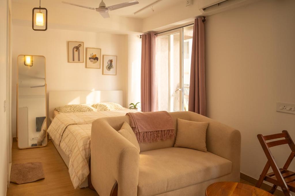 a bedroom with a bed and a couch and a window at Casa Lucia in Pune