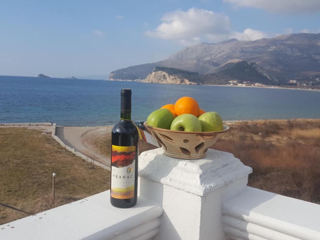 a bottle of wine sitting on a ledge with a bowl of fruit at Buljarica Bay Apartments in Petrovac na Moru