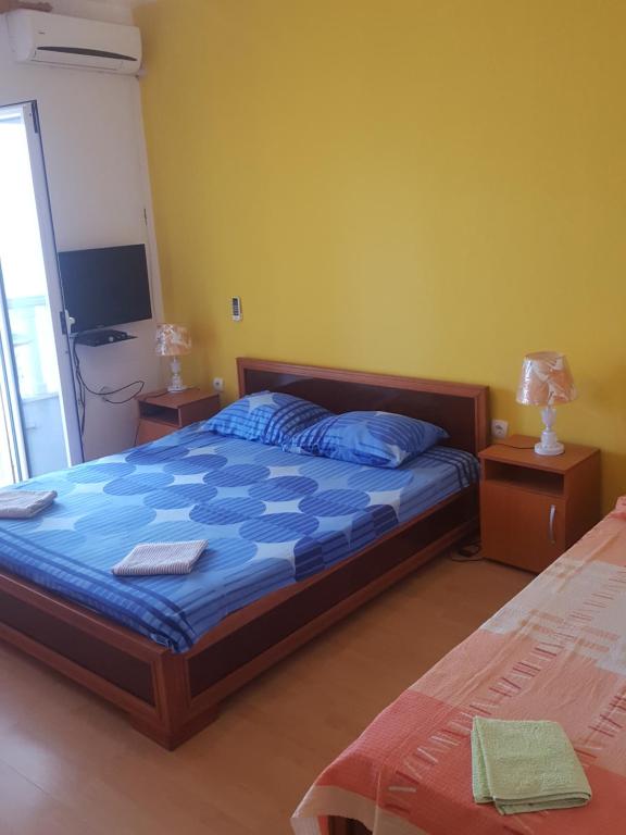 a bedroom with a bed with a blue comforter and a television at Buljarica Bay Apartments in Petrovac na Moru