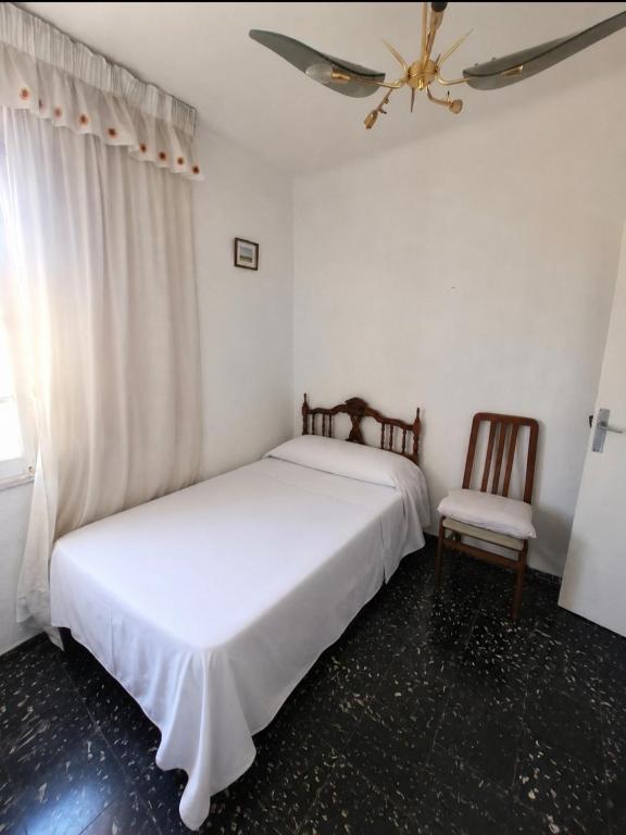two beds in a room with a window and a chair at Leydi 2 in Alicante