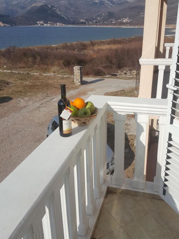 a bowl of fruit and a bottle of wine on a balcony at Buljarica Bay Apartments in Petrovac na Moru
