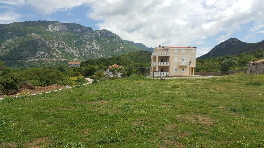a house in a field with mountains in the background at Buljarica Bay Apartments in Petrovac na Moru