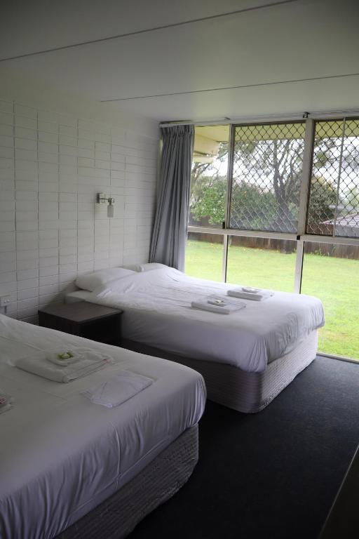 two beds in a room with a window at Hilltop Hotel in Goonellabah