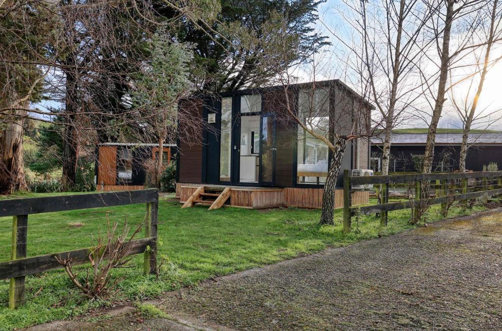 a house with a fence next to a yard at Wahi Marie X by Tiny Away in Puketitiri