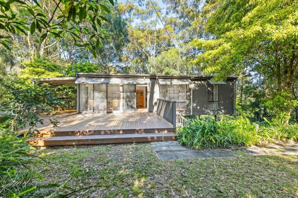 a small house with a wooden deck in a yard at The Treehouse at Long Beach in Long Beach