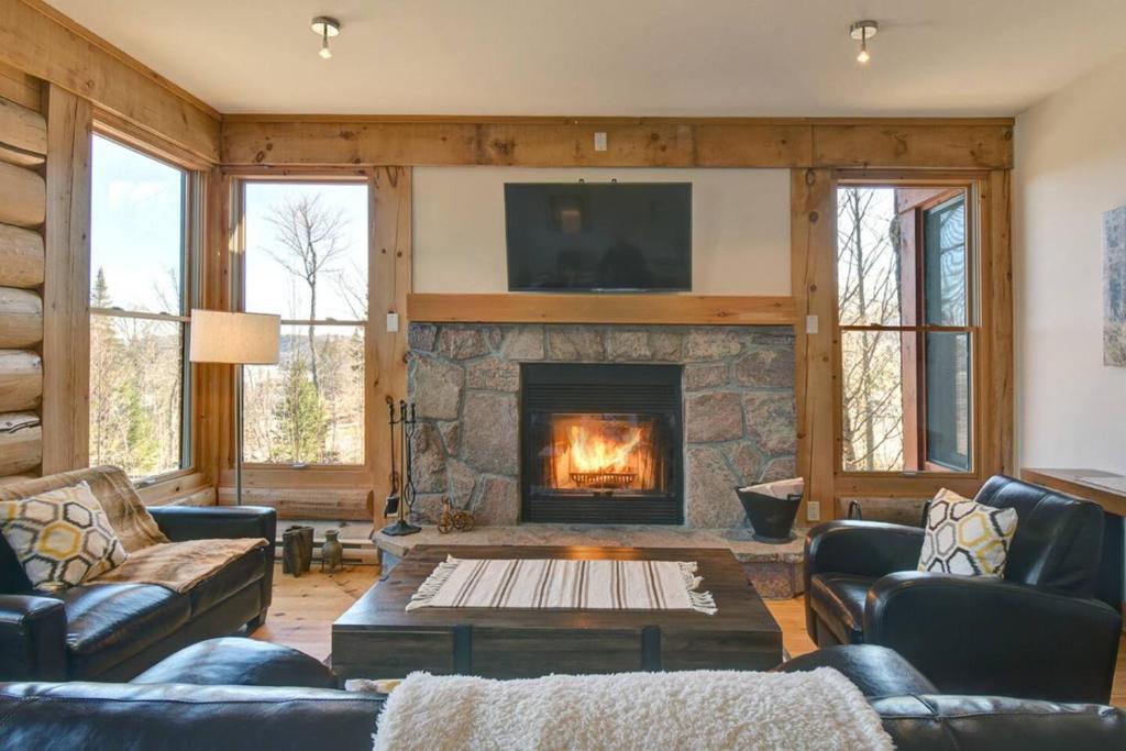 a living room with a fireplace and a tv at Luxurious Scandinavian Cottage with Private Jacuzzi in Lac-Superieur