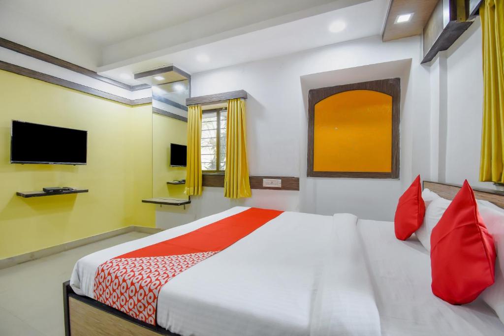 a bedroom with a bed with red pillows and a tv at Super hotel O Adri 2 in Kolkata