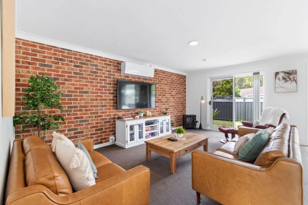 a living room with two couches and a brick wall at Light and Bright at Maloneys in Maloney's Beach