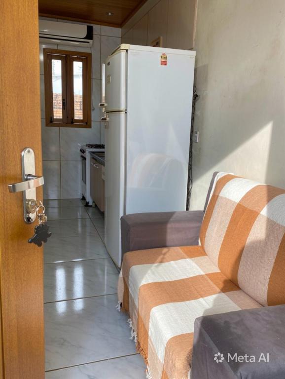 a kitchen with a refrigerator and a couch at Kitnet Completa Próx Unipampa e Centro Wi-Fi in Alegrete