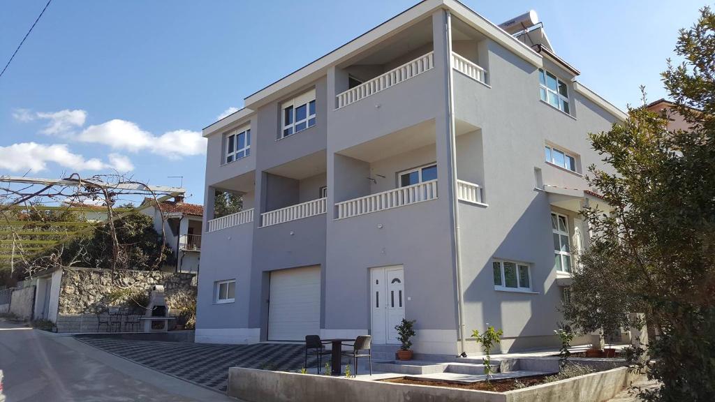 un grand bâtiment blanc avec un garage dans l'établissement Apartments Parcela, à Seget Vranjica