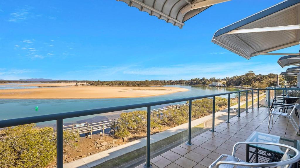 a balcony with chairs and a view of a beach at Mountains By The Sea in Nambucca Heads