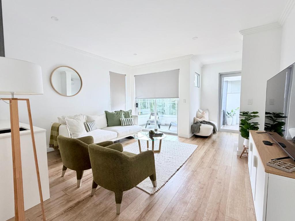 ein weißes Wohnzimmer mit Sofa und Sesseln in der Unterkunft Simplicity Terrigal in Terrigal