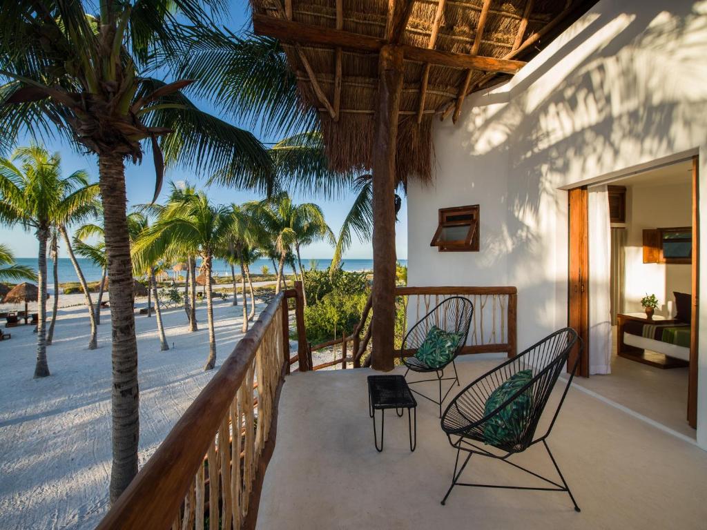 uma varanda com cadeiras e palmeiras na praia em Villas HM Palapas del Mar em Holbox