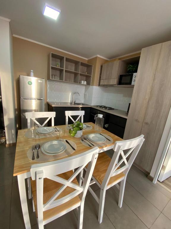 a kitchen with a wooden table with four chairs at Casa Laguna Suites in Concepción