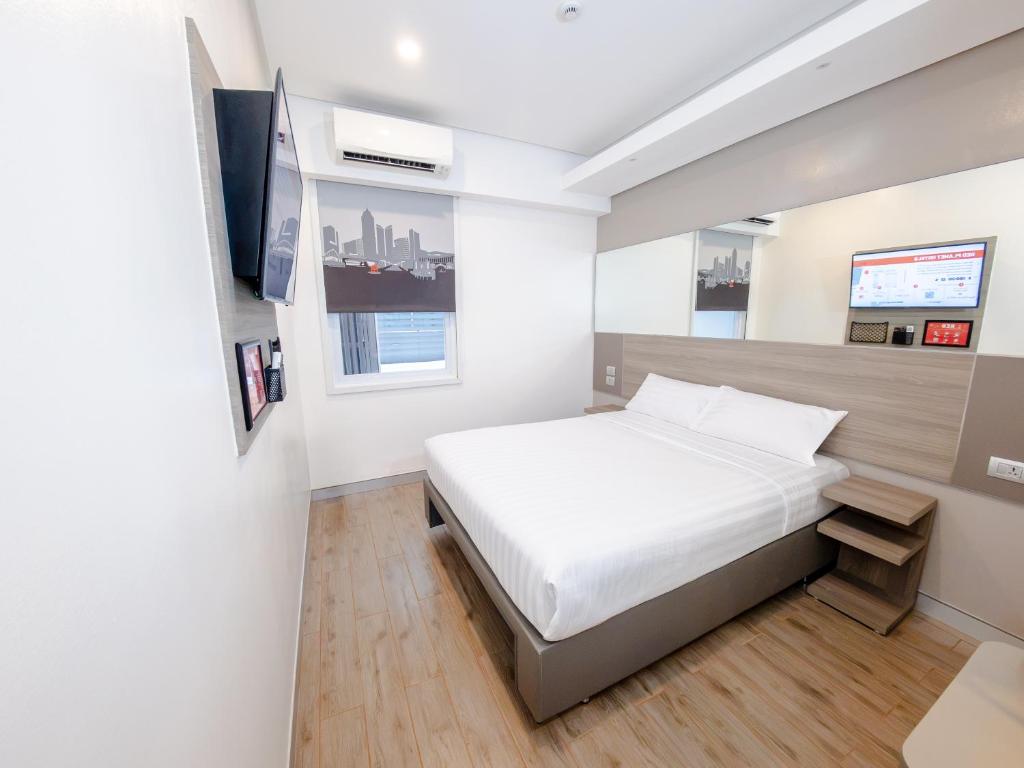 a white bedroom with a bed and a tv at Red Planet Manila Bay in Manila
