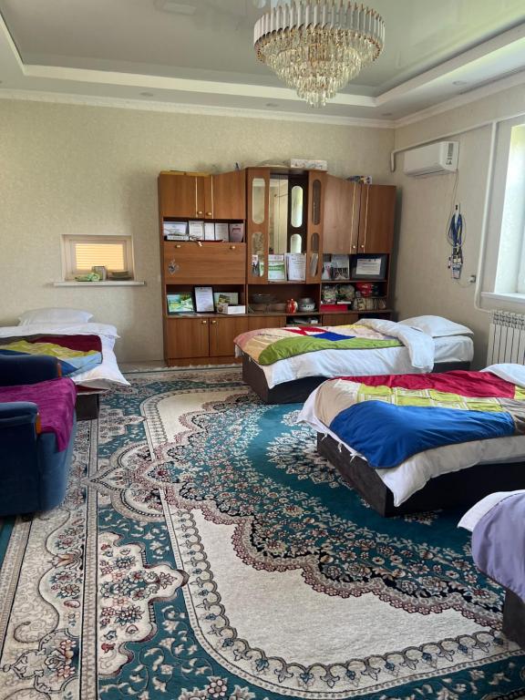 a bedroom with three beds and a large rug at Adventure Guest House in Pokrovka
