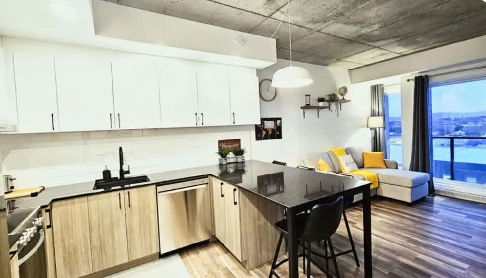 a kitchen with a counter top and a living room at Caïman - Le1006 in Quebec City