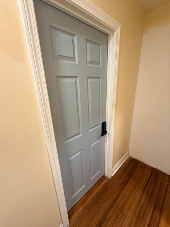 a white door in a room with a wooden floor at Grey comfort room in New London