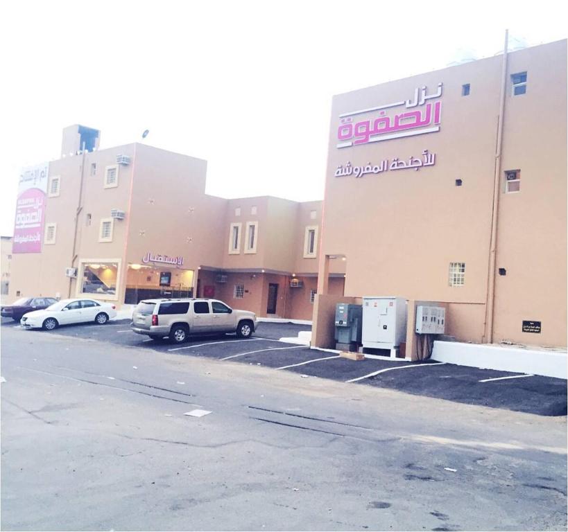 a parking lot with cars parked in front of a building at نزل الصفوة للأجنحة المفروشه بأبها in Abha
