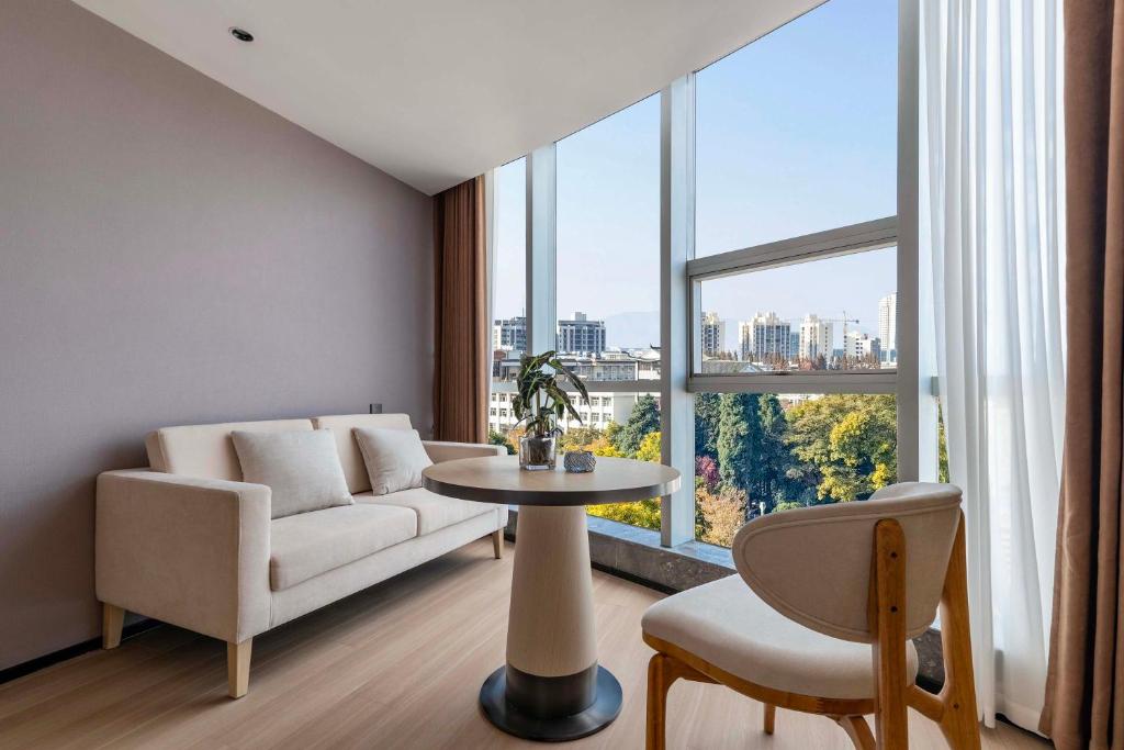 a living room with a couch and a table and a large window at YIBON INTERNATIONAL HOTEL in Guiyang