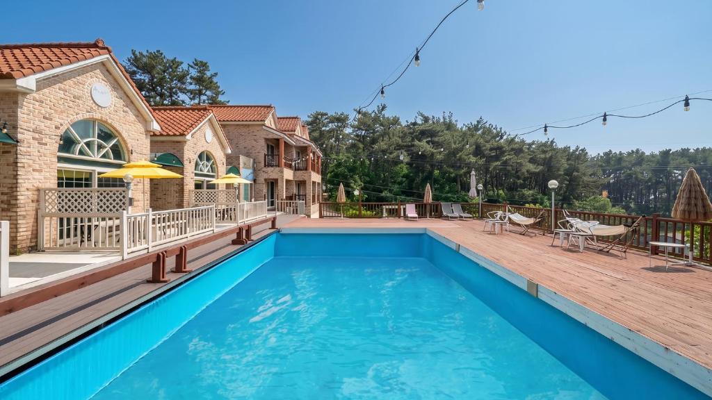 a swimming pool with a deck and a house at Taean Atirans Beach Pension in Taean