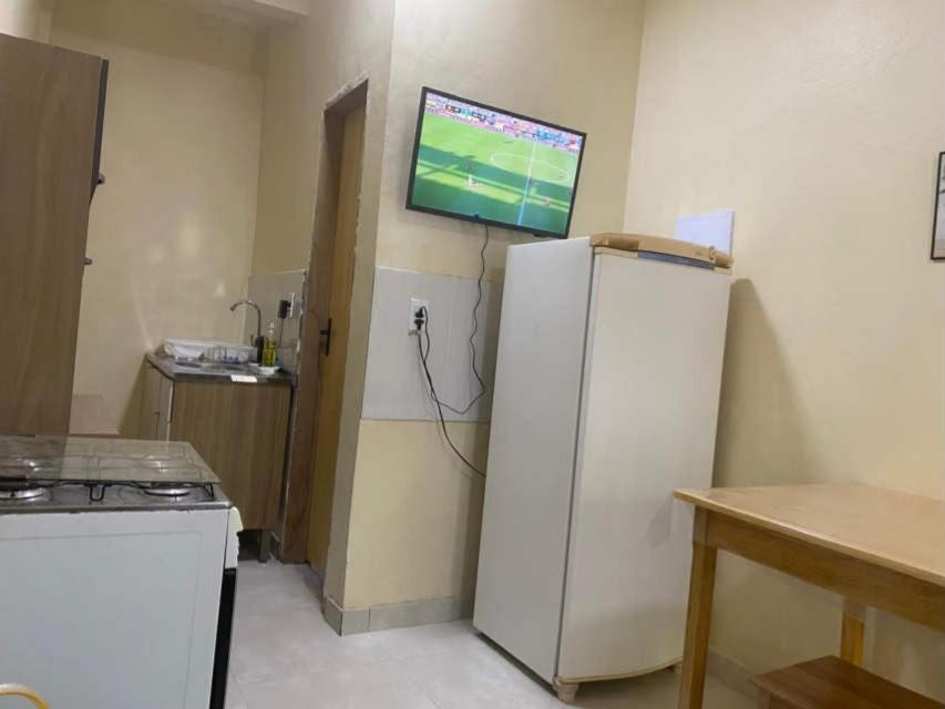 a kitchen with a white refrigerator and a tv on the wall at Apartamento Colinas in Cacoal