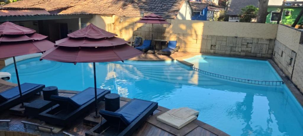 a swimming pool with chairs and umbrellas at THE PALM's BED AND BREAKFAST IN ARPORA in Arpora