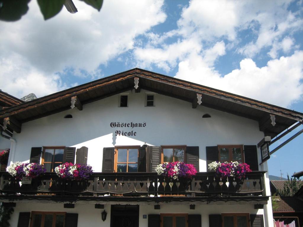 ein weißes Gebäude mit Blumen auf dem Balkon in der Unterkunft Gästehaus Nicole in Garmisch-Partenkirchen