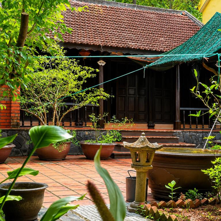 a courtyard with pots of plants and a building at Vũ Di Homestay in Hue