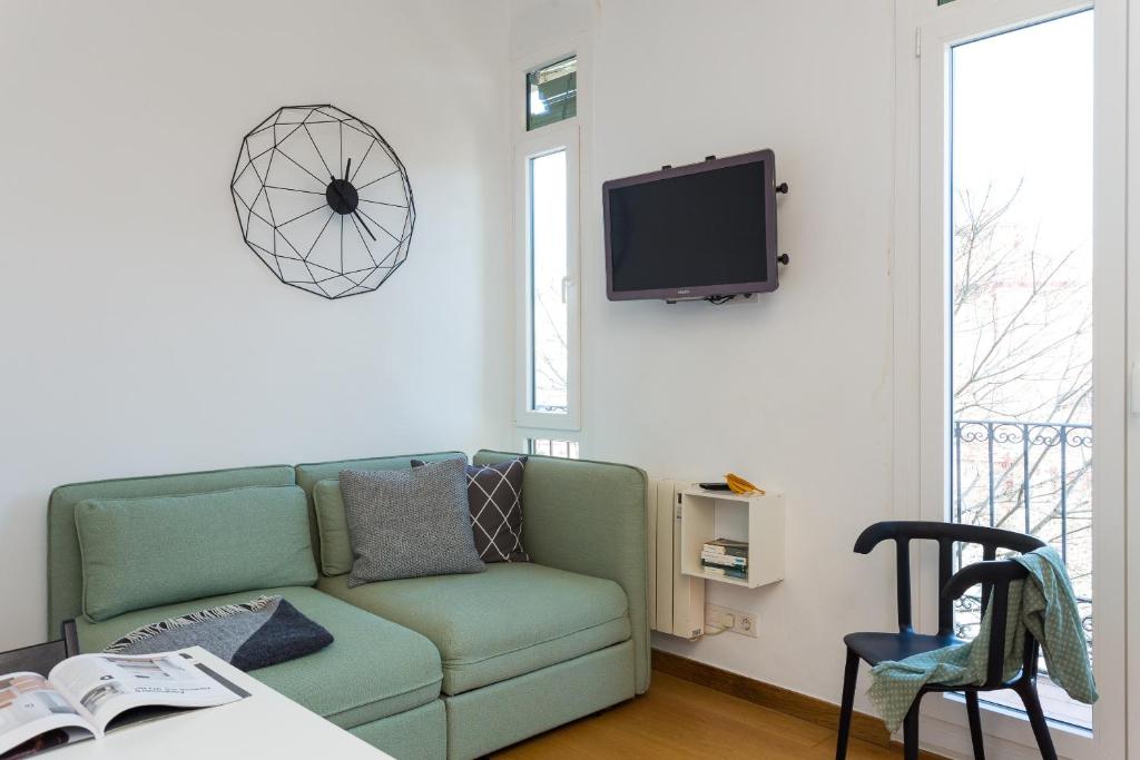 salon z kanapą i telewizorem na ścianie w obiekcie Casa Cosi Sant Antoni w Barcelonie