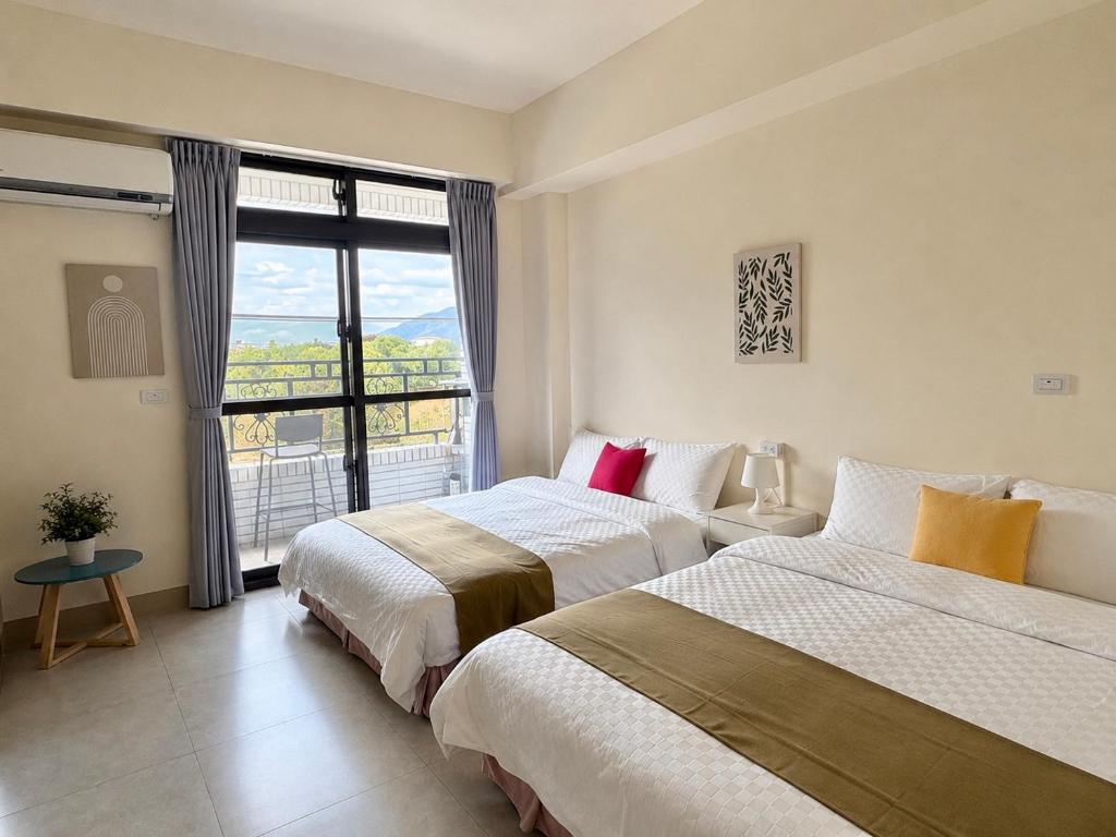 two beds in a room with a large window at 雀居民宿 in Yuli